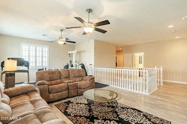 living room featuring light wood-type flooring, visible vents, baseboards, and recessed lighting