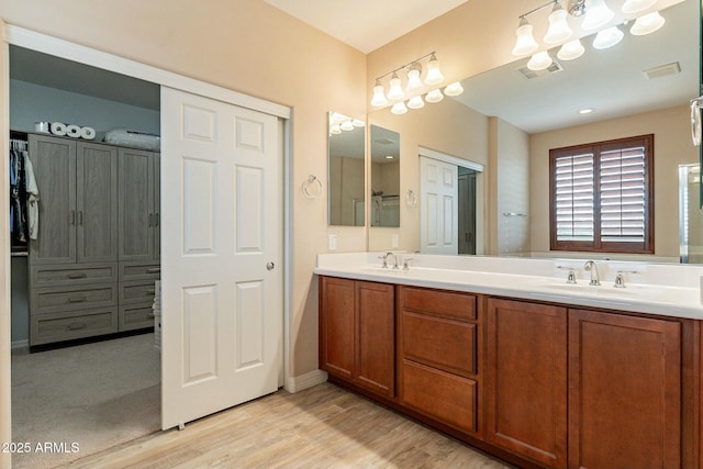 full bath featuring double vanity, a closet, visible vents, a sink, and wood finished floors