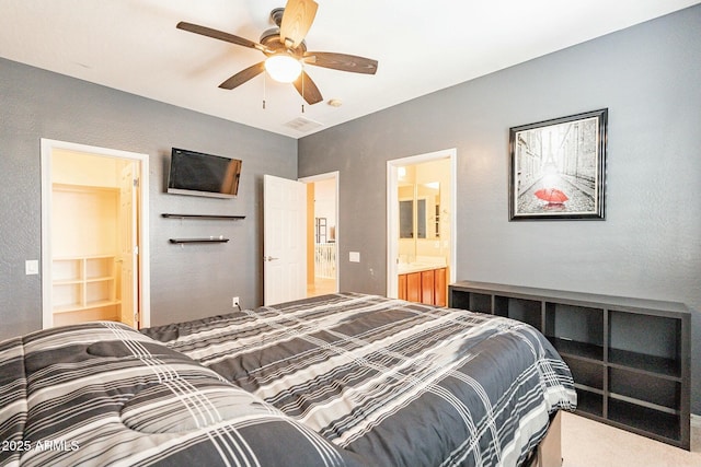 carpeted bedroom with ensuite bathroom and a ceiling fan