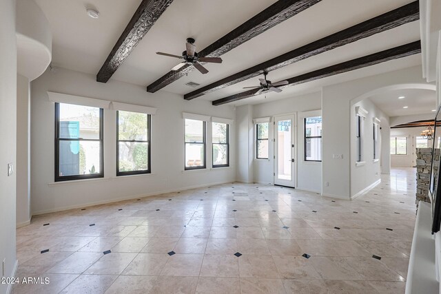 tiled empty room with ceiling fan, beamed ceiling, and plenty of natural light