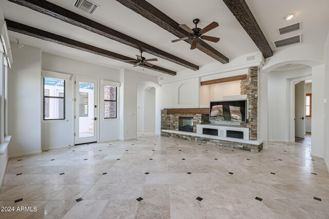 unfurnished living room with ceiling fan, a fireplace, and beam ceiling