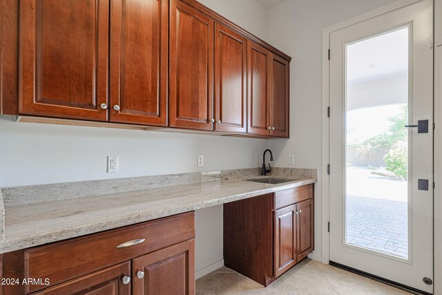 kitchen featuring light tile patterned flooring, sink, and light stone counters