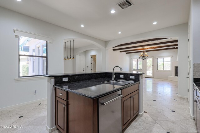 kitchen featuring beamed ceiling, a center island with sink, sink, and a healthy amount of sunlight