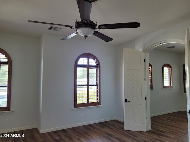 spare room with ceiling fan, plenty of natural light, and dark wood-type flooring