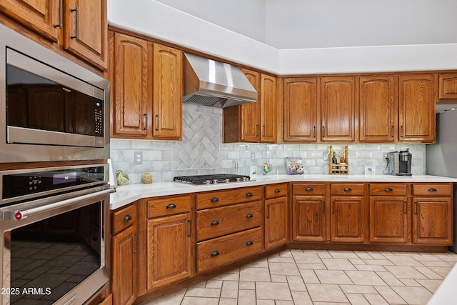 kitchen featuring stainless steel appliances, wall chimney range hood, and backsplash