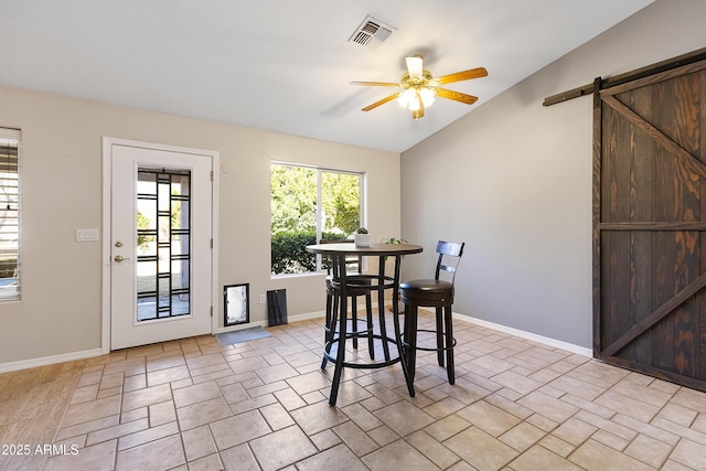 dining space featuring lofted ceiling, a barn door, and ceiling fan