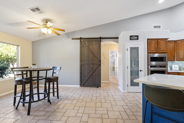 dining area with ceiling fan, lofted ceiling, and a barn door