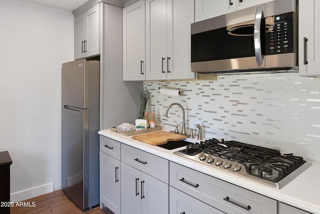 kitchen featuring dark wood-type flooring, appliances with stainless steel finishes, sink, and backsplash