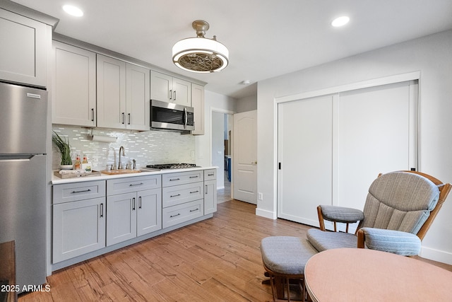 kitchen featuring sink, gray cabinetry, tasteful backsplash, appliances with stainless steel finishes, and light hardwood / wood-style floors