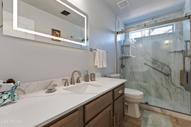 bathroom with vanity, a shower with door, and toilet