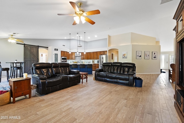 living room featuring ceiling fan, a barn door, high vaulted ceiling, and light hardwood / wood-style floors