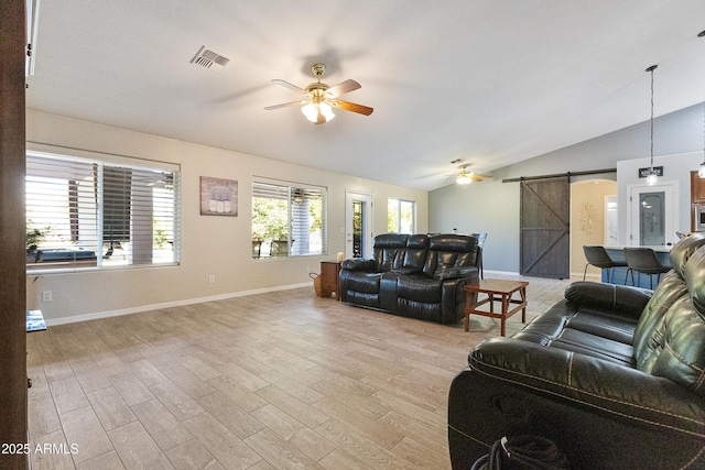 living room with lofted ceiling, a barn door, ceiling fan, and light wood-type flooring