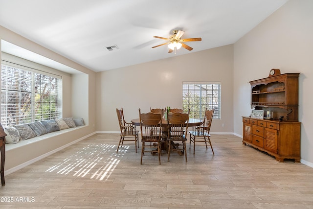 dining room featuring vaulted ceiling, a wealth of natural light, and light hardwood / wood-style flooring