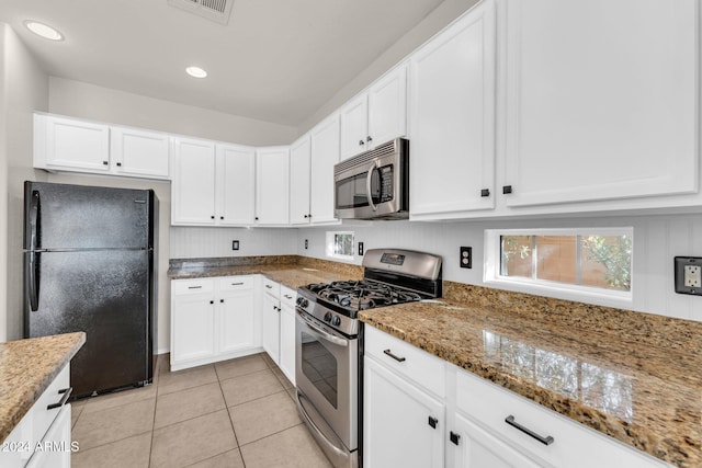 kitchen featuring appliances with stainless steel finishes, stone countertops, white cabinetry, and light tile patterned flooring