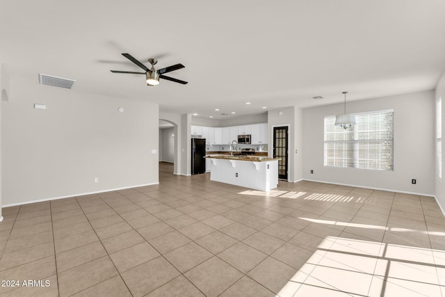 unfurnished living room with light tile patterned floors and ceiling fan with notable chandelier