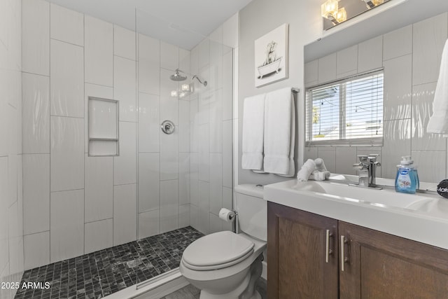 bathroom featuring vanity, toilet, and tiled shower