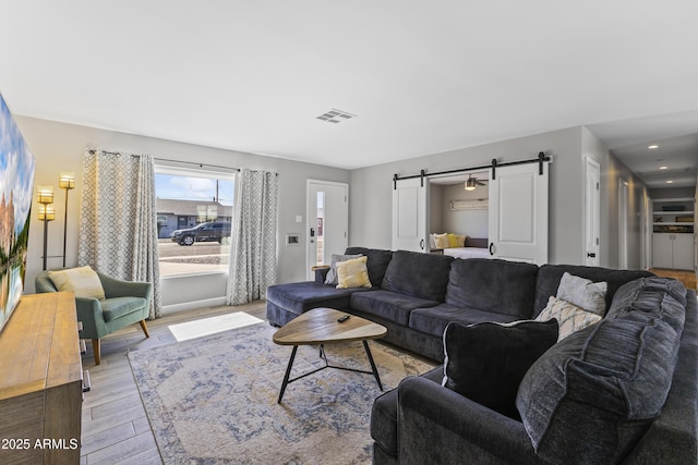 living room featuring a barn door and light hardwood / wood-style floors