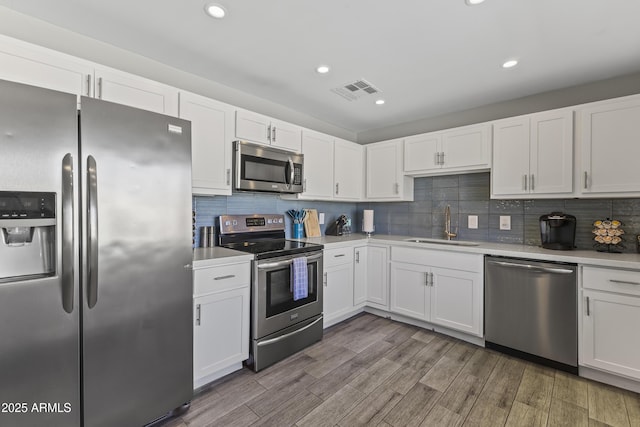 kitchen with white cabinetry, appliances with stainless steel finishes, sink, and tasteful backsplash