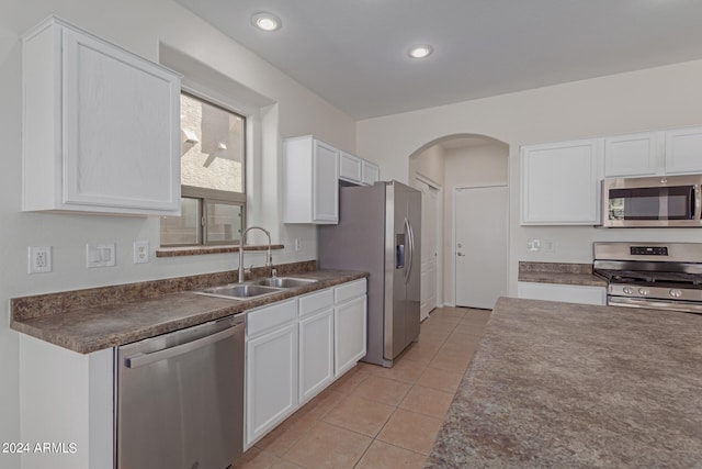 kitchen featuring white cabinets, light tile patterned flooring, appliances with stainless steel finishes, and sink