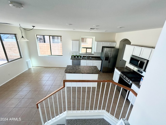 kitchen featuring white cabinets, sink, light tile patterned floors, a kitchen island, and stainless steel appliances