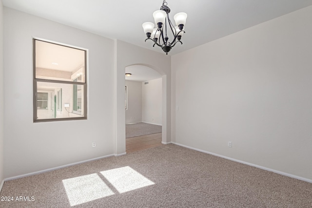 empty room featuring carpet and a notable chandelier