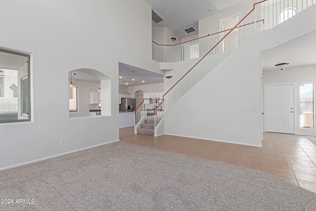 unfurnished living room with light carpet and a towering ceiling