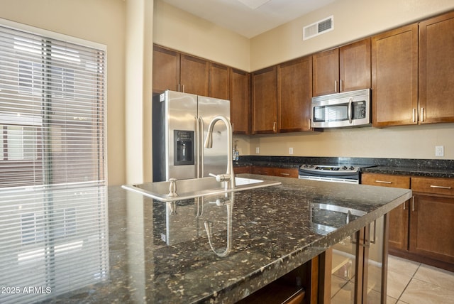 kitchen with light tile patterned flooring, stainless steel appliances, and dark stone countertops