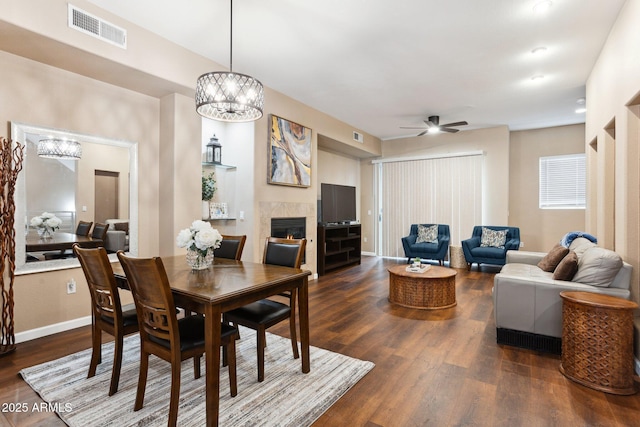 dining room with a tile fireplace, dark hardwood / wood-style floors, and ceiling fan