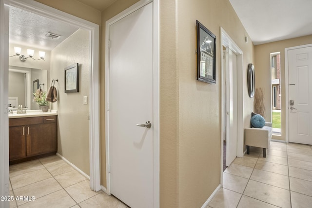 hallway featuring sink, a textured ceiling, and light tile patterned flooring