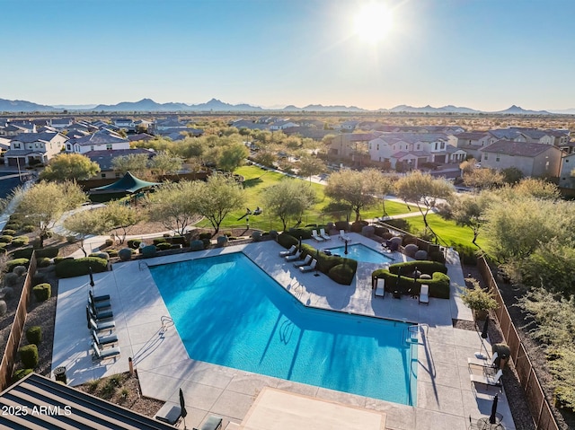 pool with a patio area, a residential view, a mountain view, and fence