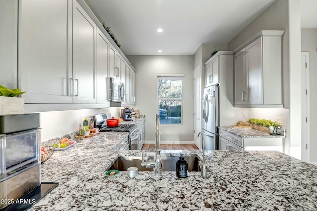 kitchen featuring a sink, white cabinetry, recessed lighting, stainless steel appliances, and light stone countertops