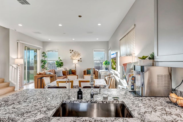 kitchen featuring light stone countertops, visible vents, recessed lighting, a sink, and open floor plan