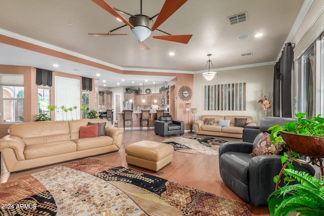 living room with hardwood / wood-style flooring, ceiling fan, and ornamental molding