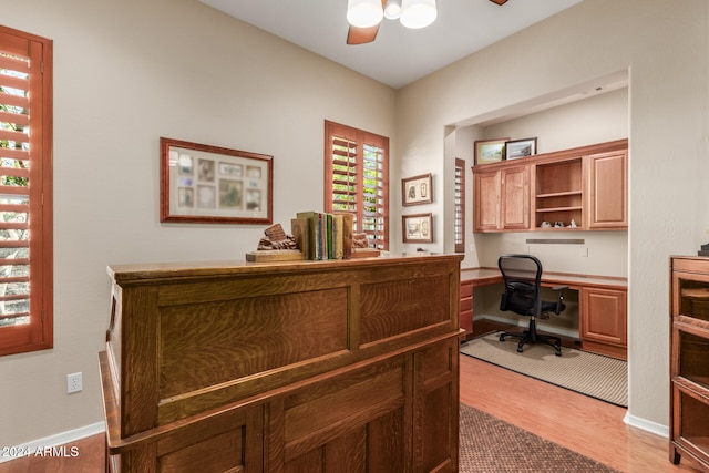 home office featuring built in desk, light hardwood / wood-style flooring, and ceiling fan