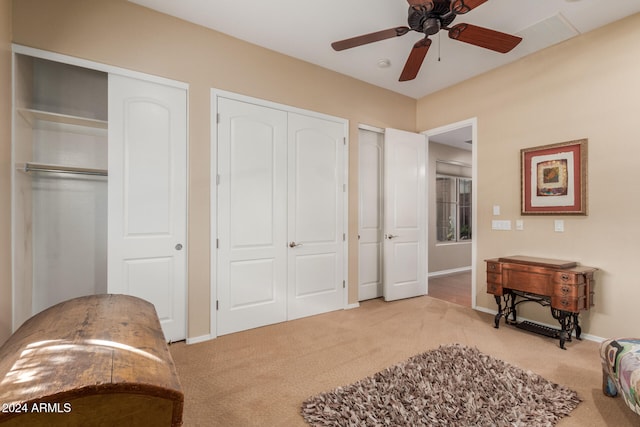 carpeted bedroom with ceiling fan and two closets