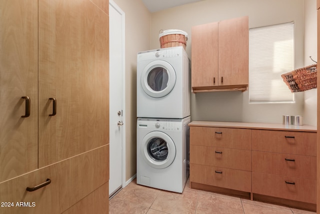 washroom featuring light tile patterned floors, cabinets, and stacked washer / drying machine