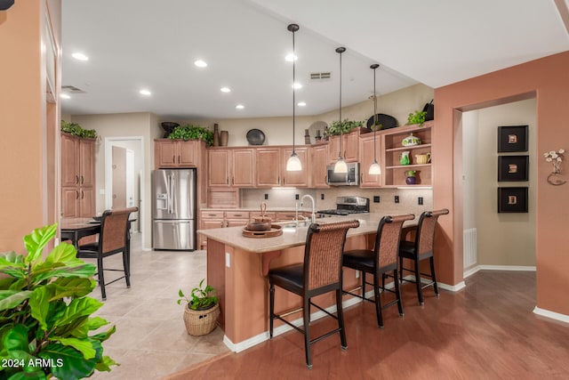 kitchen featuring hanging light fixtures, backsplash, kitchen peninsula, a breakfast bar, and appliances with stainless steel finishes