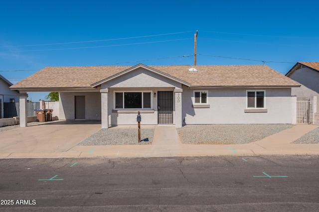 ranch-style house featuring concrete driveway, stucco siding, fence, and an attached carport