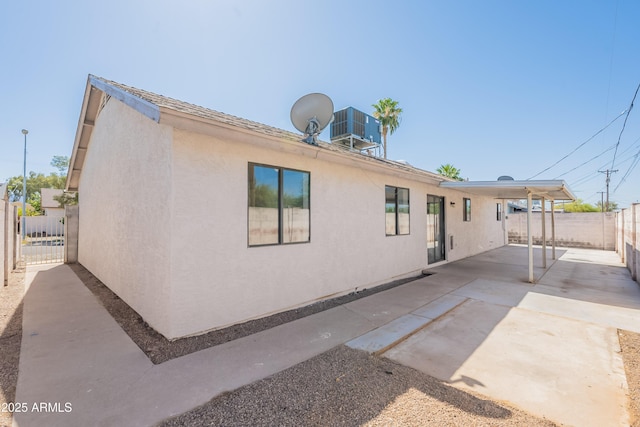 back of property with a fenced backyard, a patio, stucco siding, and central AC