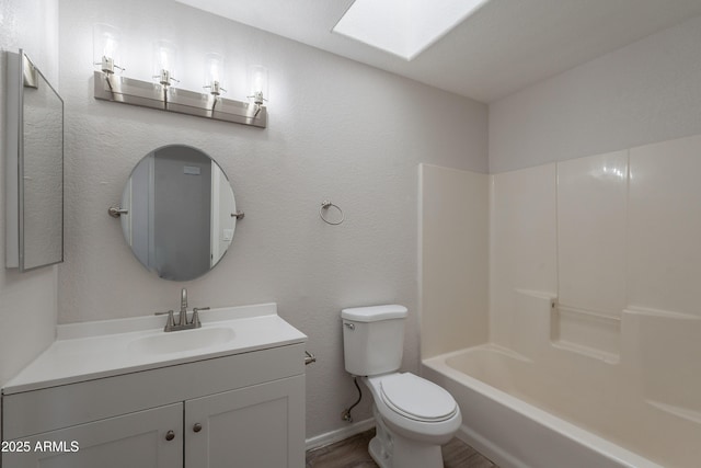 full bath featuring toilet, wood finished floors, a skylight, baseboards, and vanity