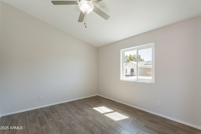 spare room with baseboards, vaulted ceiling, dark wood-style flooring, and a ceiling fan