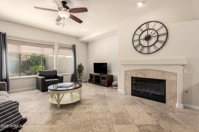 9747 S 182nd Dr, Goodyear, AZ 85338 - living room with stone tile floors, ceiling fan, baseboards, and a tile fireplace