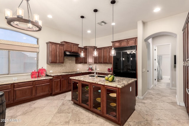 9747 S 182nd Dr, Goodyear, AZ 85338 - kitchen with under cabinet range hood, visible vents, decorative backsplash, arched walkways, and black appliances