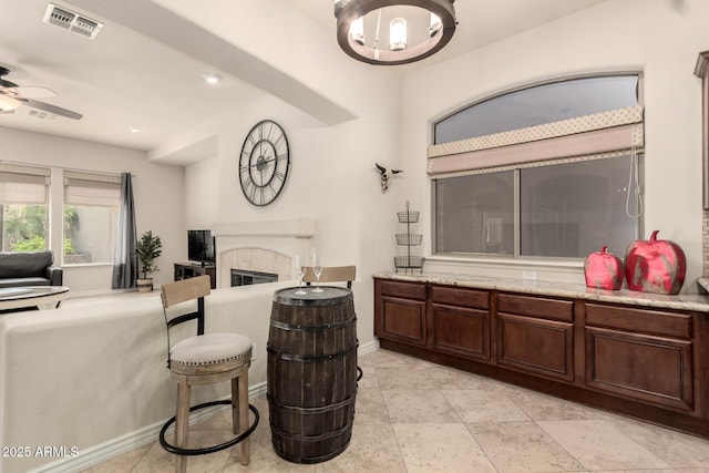 9747 S 182nd Dr, Goodyear, AZ 85338 - living area featuring visible vents, baseboards, a tile fireplace, and ceiling fan with notable chandelier