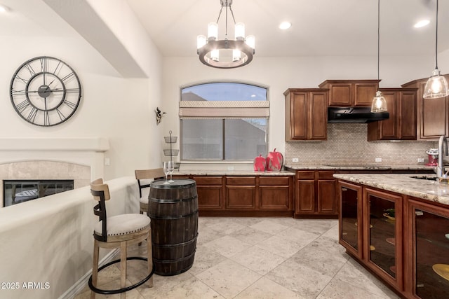 9747 S 182nd Dr, Goodyear, AZ 85338 - kitchen with light stone countertops, tasteful backsplash, a chandelier, under cabinet range hood, and a sink