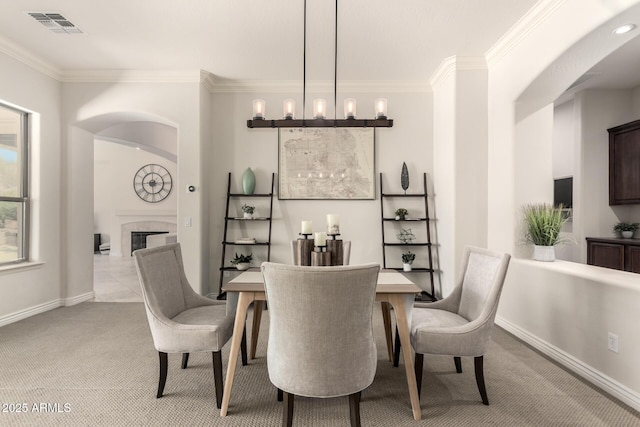 9747 S 182nd Dr, Goodyear, AZ 85338 - dining space with light colored carpet, ornamental molding, visible vents, and a glass covered fireplace