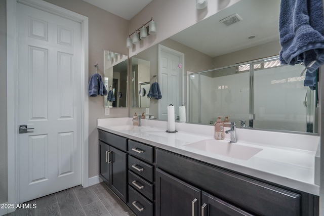 bathroom featuring a sink, double vanity, wood finished floors, and visible vents