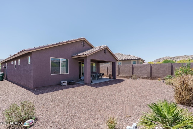 rear view of property featuring a tiled roof, a patio, fence, and stucco siding