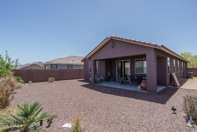 rear view of property with a tile roof, stucco siding, a fenced backyard, cooling unit, and a patio