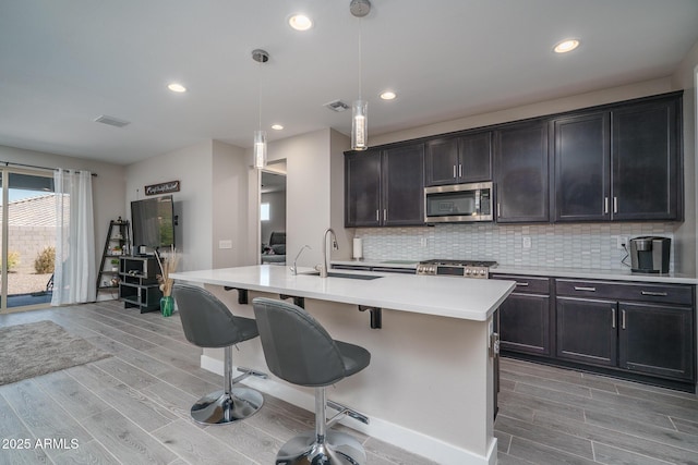 kitchen with stainless steel microwave, visible vents, a sink, and light wood-style floors
